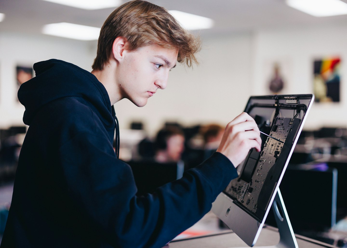 Un hombre repara una placa de circuito de computadora en un laboratorio de aulas.