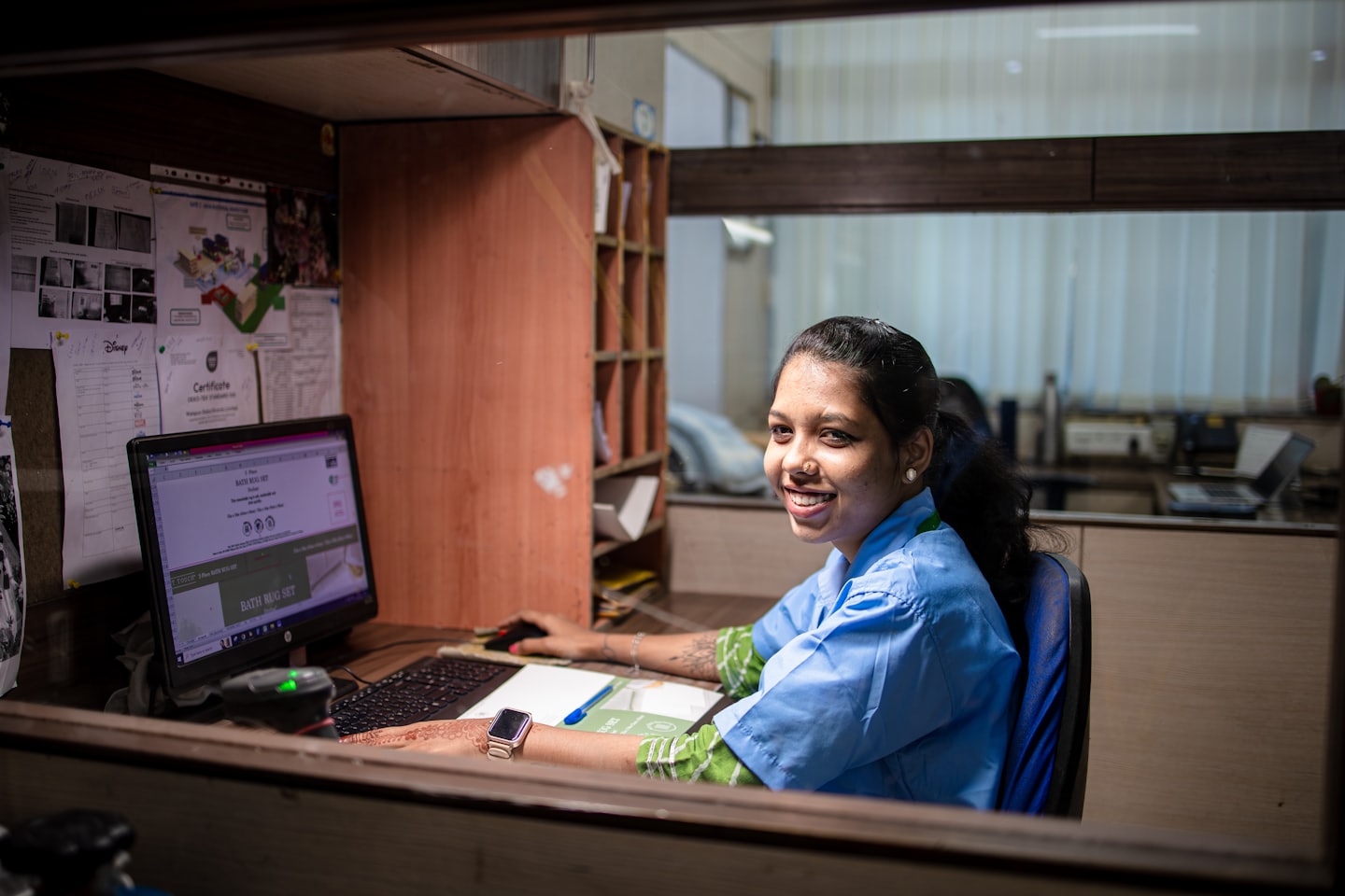 Mujer con uniforme azul trabajando en su computadora de oficina.